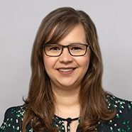 Frau mit Brille lächelt vor neutralem Hintergrund